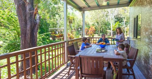 a family sitting at a table on a deck at Litchfield Tourist Park in Batchelor