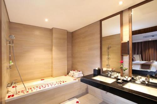 a bathroom with a tub and two sinks and a bed at Swiss-Belinn Karawang in Karawang