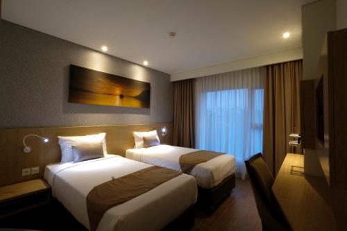 a hotel room with two beds and a television at Hotel AYOLA Lippo Cikarang in Cikarang