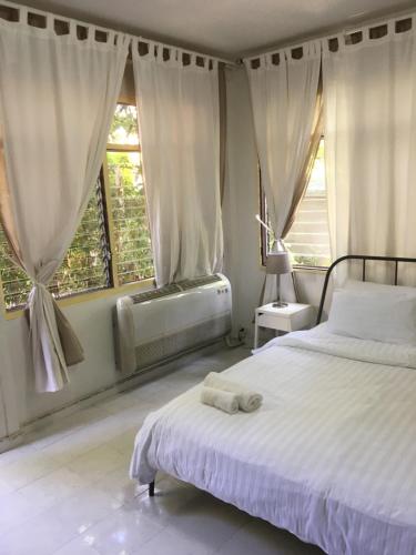 a bedroom with a white bed and two windows at Many Trees in Bangkok