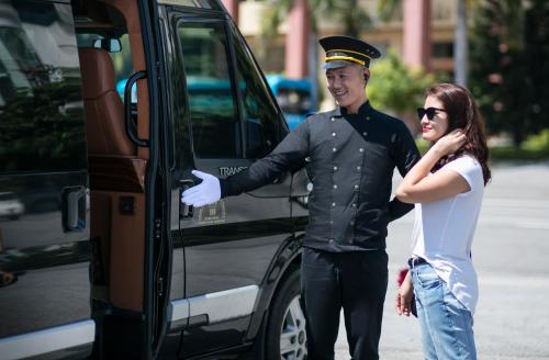 a man and a woman standing next to a van at Emperor Cruises Legacy Ha Long in Ha Long