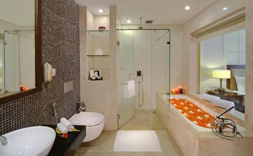 y baño con bañera, aseo y ducha. en Country Inn & Suites by Radisson, Goa Candolim, en Candolim