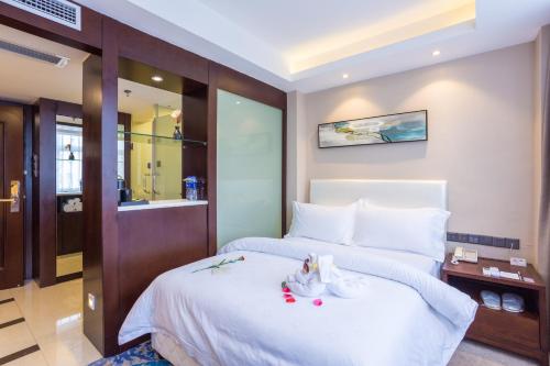 a hotel room with a bed with white sheets at Metropolo Jinjiang Xuzhou Railway Station Suning Plaza Chudu in Xuzhou