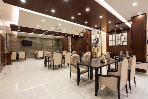 a dining room with tables and chairs and a television at Metropolo Jinjiang Xuzhou Railway Station Suning Plaza Chudu in Xuzhou