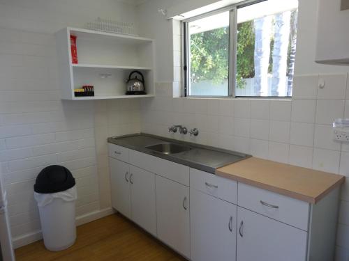 eine weiße Küche mit Spüle und Fenster in der Unterkunft Archipelago Apartments Esperance in Esperance