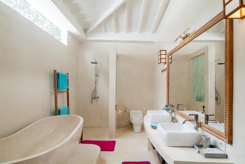 a bathroom with a tub and a sink and a mirror at De'Coco Villa in Gili Air