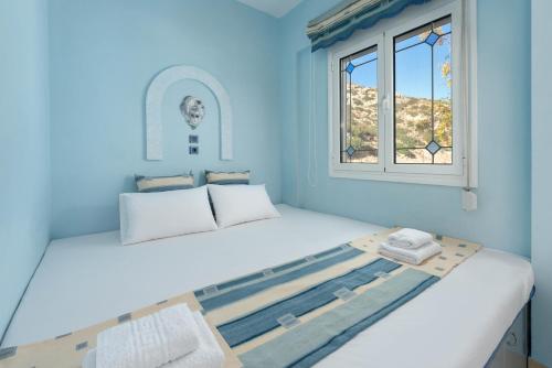 een blauwe kamer met een bed en een raam bij Stella Beach House in Archangelos