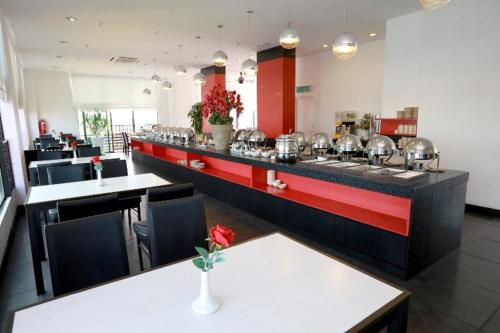 a restaurant with a long counter with tables and chairs at Crystal Lodge in Kota Bharu
