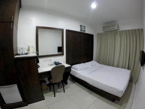 a hotel room with a bed and a desk and a bed and a mirror at Crystal Lodge in Kota Bharu