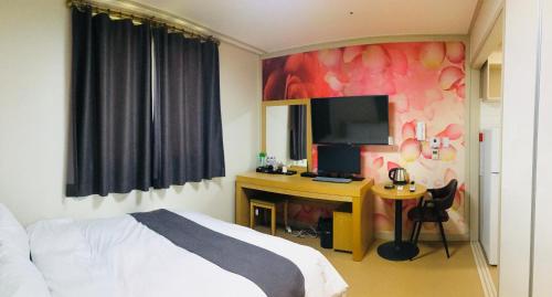 平沢市にあるHotel Joy near Camp Humphresのベッドとテレビ付きの机のある寝室