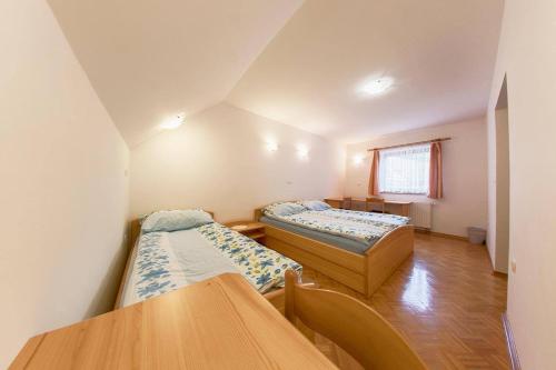 Habitación con 2 camas y mesa. en Farm Stay Loger en Ljubno