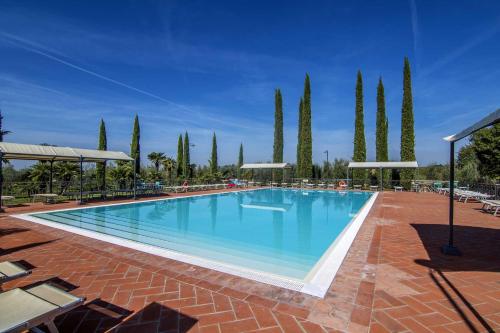 a large swimming pool in a resort with trees at Agriturismo Le Gallozzole in Monteriggioni