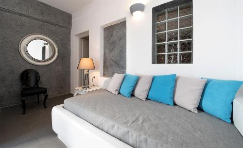 a bedroom with a couch with blue and white pillows at Philippion Boutique Hotel in Fira