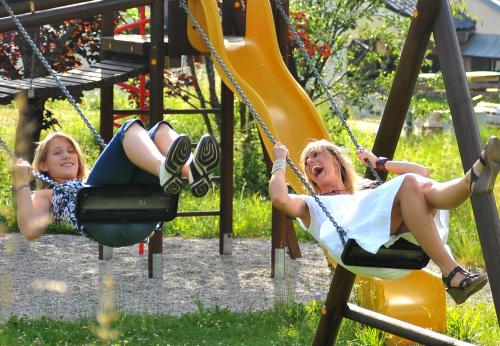 two girls playing on swings at a playground at Familienhotel Sonngastein in Bad Gastein