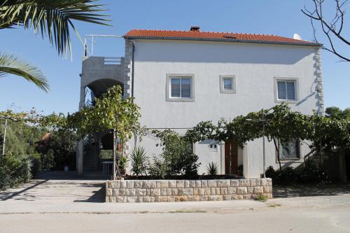 una casa blanca con una palmera delante de ella en Apartments Sirena Korčula, en Korčula