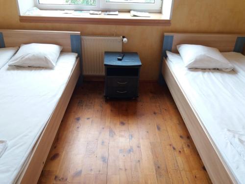 two beds in a room with a table between them at Hotel Erfolg in Daugavpils