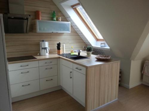 a kitchen with white cabinets and a window in a attic at Strandhaus Buchtmitte in Haffkrug
