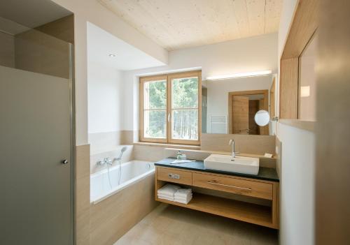 uma casa de banho com um lavatório e uma banheira em Naturhotel Bauernhofer em Heilbrunn