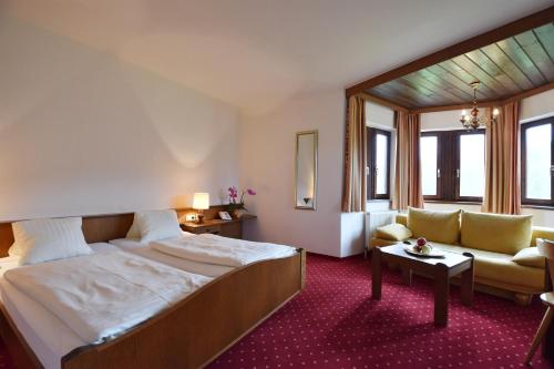ein Hotelzimmer mit einem Bett und einem Sofa in der Unterkunft Hotel Restaurant Stigenwirth in Krakauebene