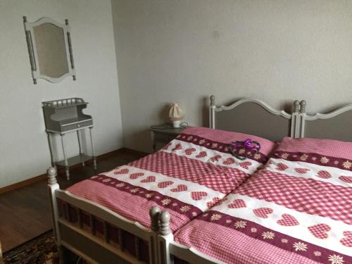 - une chambre avec un lit et une couette rose dans l'établissement Le Relais des Mayens de Chamoson, à Ovronnaz