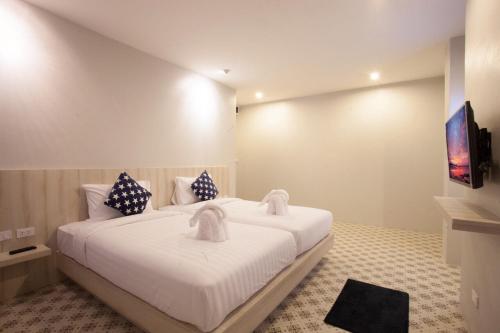 a bedroom with a large white bed with two pillows at Nature Pine Residence in Rawai Beach