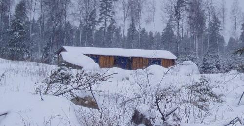 a barn covered in snow in a snowy field at Timjan Forest Resort in Nydala