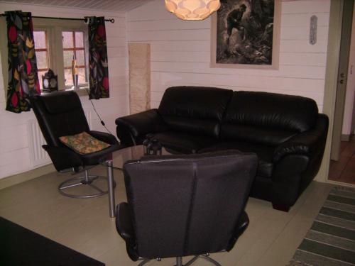 a living room with a black leather couch and two chairs at Timjan Forest Resort in Nydala