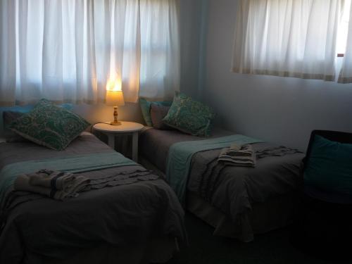 a room with two beds and a lamp on a table at A1 Kynaston Guest House bed and breakfast or self catering in Jeffreys Bay
