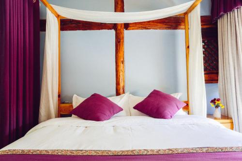 a white bed with purple pillows in a bedroom at Log Cabin in Dali