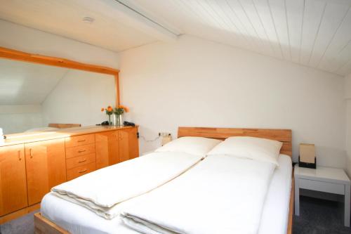 a bedroom with a large white bed and wooden cabinets at Hotel Brandl in Bad Wörishofen