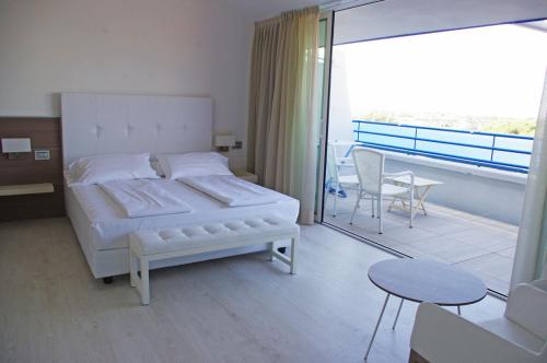 a bedroom with a white bed and a balcony at Grand Hotel Esplanada in Bibione