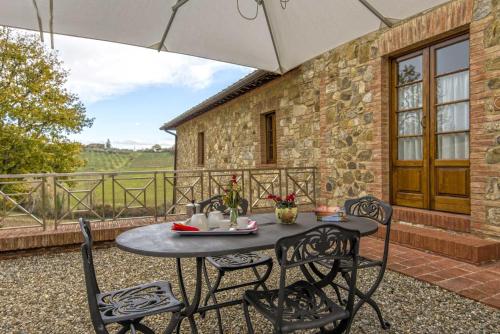 a table and chairs on a patio with a stone wall at Agriturismo Le Gallozzole in Monteriggioni