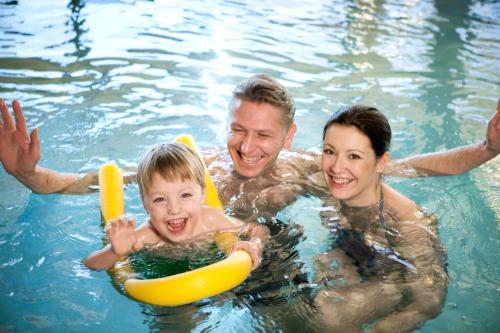 a man and a woman and a child in a swimming pool at Naturhotel Bauernhofer in Heilbrunn