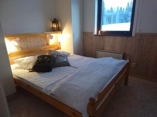 a bedroom with a large bed with a backpack on it at Fjällsikten Apartment in Granberget