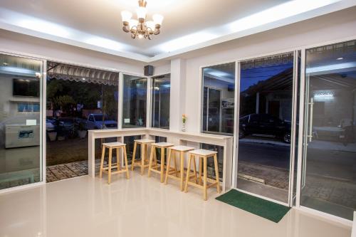 a kitchen with a bar with stools and windows at Lin House in Thalang