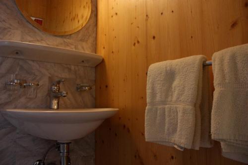 a bathroom with a sink and towels on a wall at Hotel de Commune in Dombresson