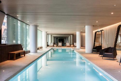 uma piscina num edifício com cadeiras e mesas em Winston Apartments Docklands em Melbourne