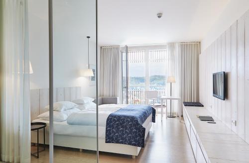 エーレンハウゼンにあるローイシウム ワイン ＆ スパ リゾート ズュートシュタイヤーマルクのベッドとテレビが備わるホテルルームです。
