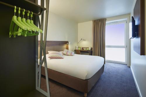 a bedroom with a bed and a window and a bed with onions at Campanile Paris Sud Saclay- Gif sur yvette in Saclay