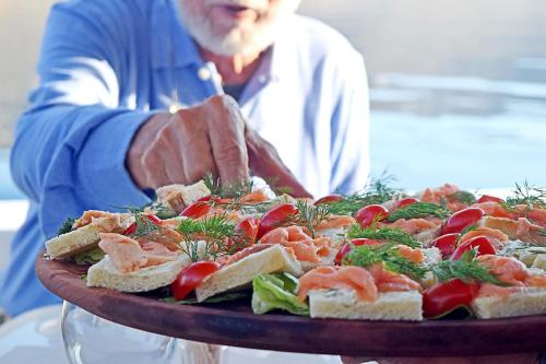 a man holding a tray of food on a table at Aegialis Hotel & Spa in Aegiali