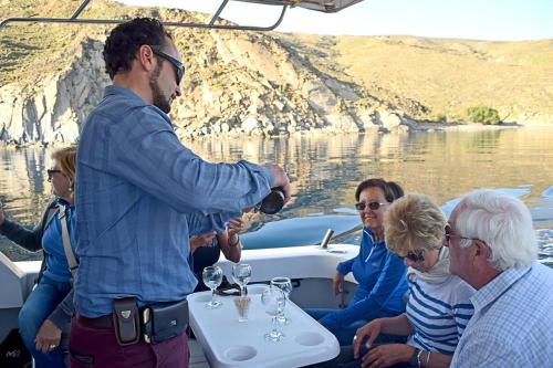 a man standing on a boat pouring a glass of wine at Aegialis Hotel & Spa in Aegiali