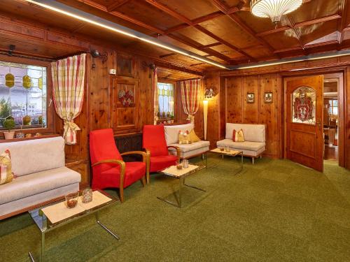 a living room filled with furniture and red chairs at Hotel Zum Hirschen in Längenfeld