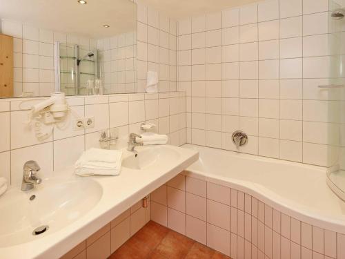 a white bathroom with a sink and a tub at Hotel Zum Hirschen in Längenfeld