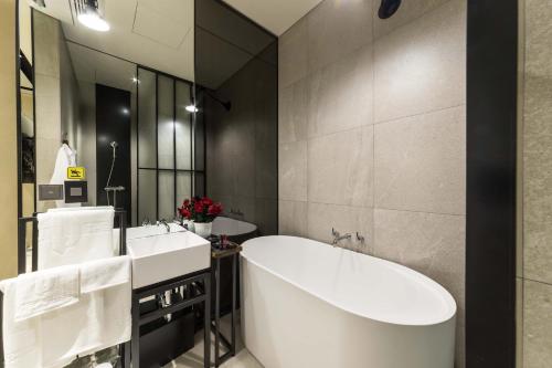 a bathroom with a tub and two sinks and a mirror at Hotel the Artist Dongdaemun in Seoul