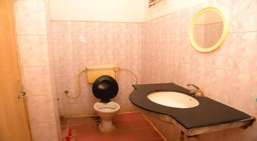 W łazience znajduje się umywalka oraz toaleta z lustrem. w obiekcie Hotel Vishnu Residency w mieście Visakhapatnam