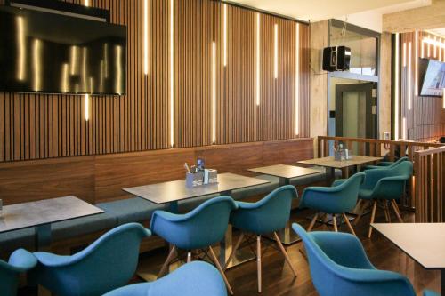 a dining room with tables and blue chairs at H24 Berlin Lichtenberg in Berlin