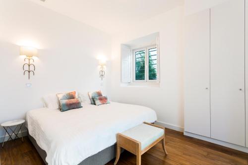 a white bedroom with a white bed and a window at Chalet Estoril Luxury Apartments in Estoril