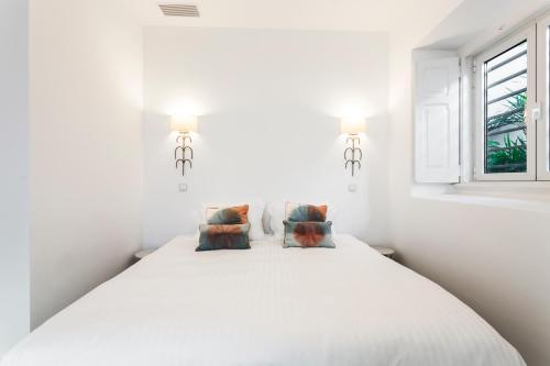 a white bedroom with a large bed with two pillows at Chalet Estoril Luxury Apartments in Estoril