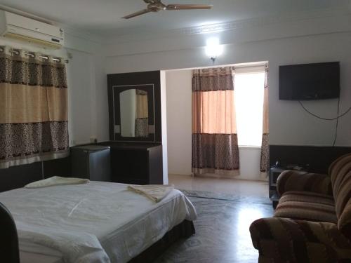 a bedroom with a bed and a couch and a mirror at Sai Pavilion in Puttaparthi