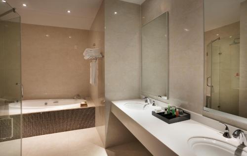 a bathroom with a tub and a sink and a shower at President Hotel at Umodzi Park in Lilongwe
